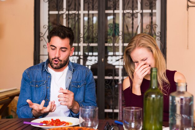 Feliz pareja joven disfrutando de comida en el restaurante