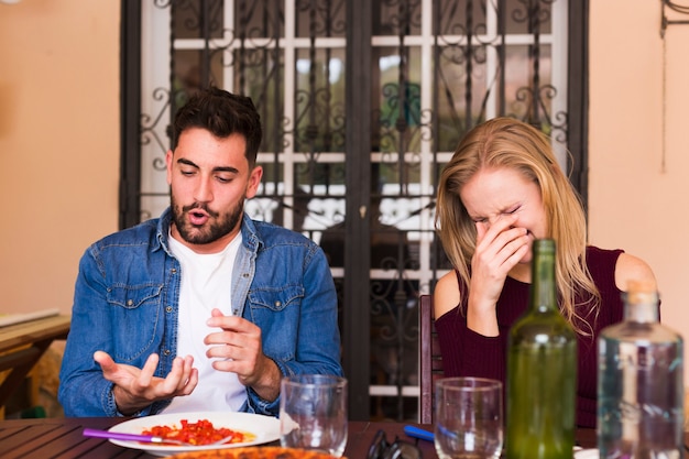 Feliz pareja joven disfrutando de comida en el restaurante