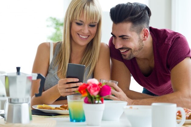 Feliz pareja joven disfrutando de desayuno en la cocina.