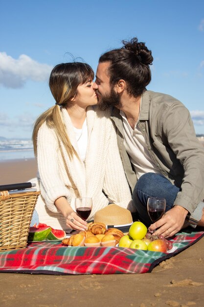 Feliz pareja joven disfrutando de un picnic a la orilla del mar