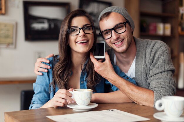 Feliz pareja joven escuchando la voz desde el teléfono móvil