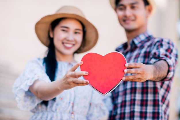 Feliz pareja joven está sosteniendo corazones de papel rojo