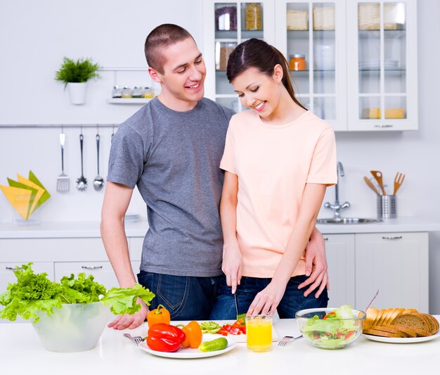 Feliz pareja joven haciendo un desayuno juntos en la cocina