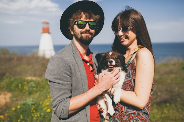 Feliz pareja joven inconformista elegante enamorado caminando con perro en campo