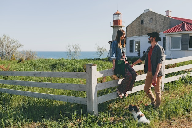 Feliz pareja joven inconformista elegante enamorado caminando con perro en campo