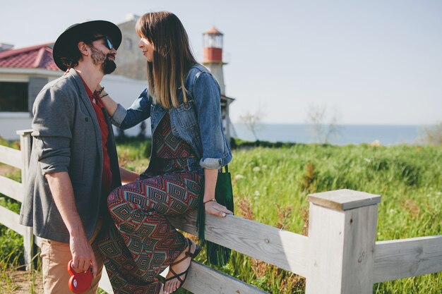 Feliz pareja joven inconformista con estilo enamorado caminando en el campo, moda boho de estilo veraniego