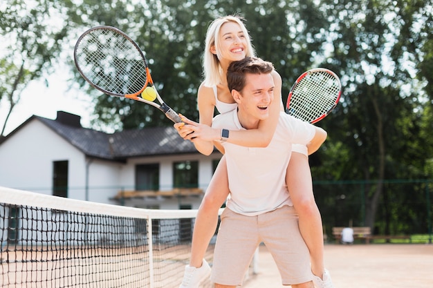 Feliz pareja joven jugando tenis