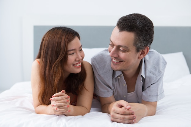 Feliz pareja joven mirando el uno al otro en la cama