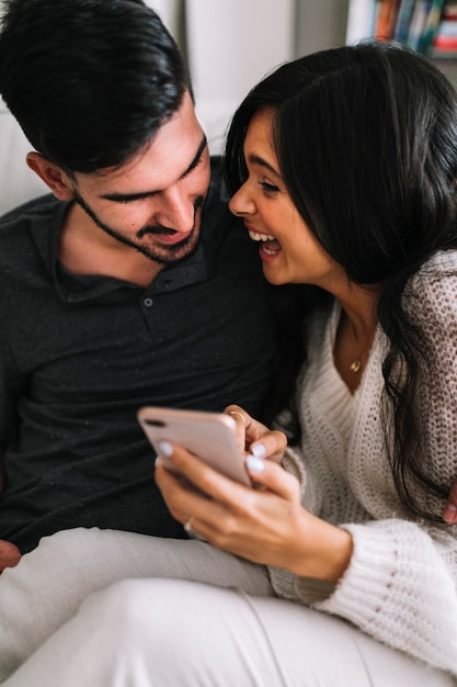 Feliz pareja joven mirando teléfono móvil