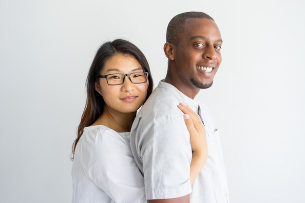 Feliz pareja joven multiétnica emocionada mirando a cámara.