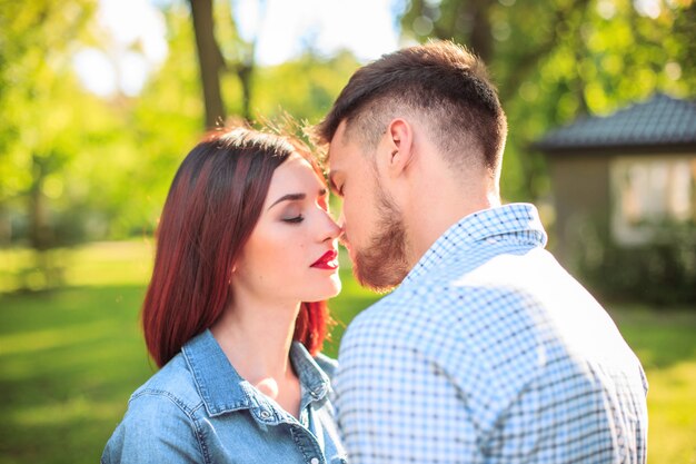 Feliz pareja joven en el parque de pie y riendo en el brillante día soleado