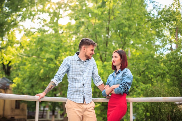 Feliz pareja joven en el parque de pie y riendo en el brillante día soleado