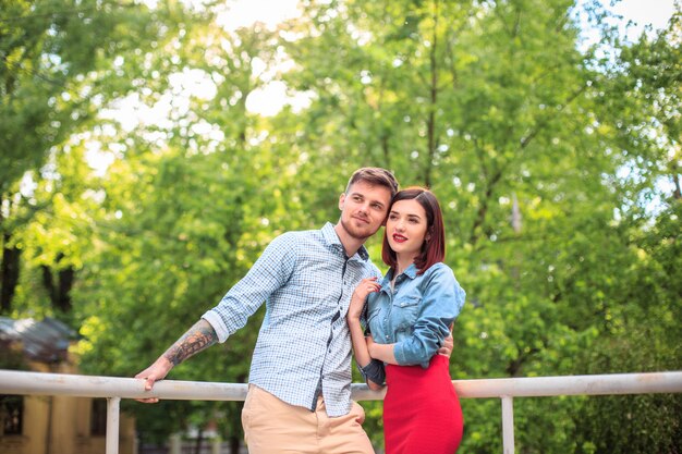 Foto gratuita feliz pareja joven en el parque de pie y riendo en el brillante día soleado