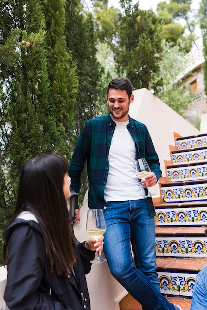 Feliz pareja joven de pie en la escalera con vaso de bebidas