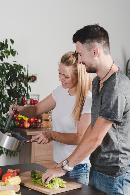 Feliz pareja joven preparando comida en la cocina