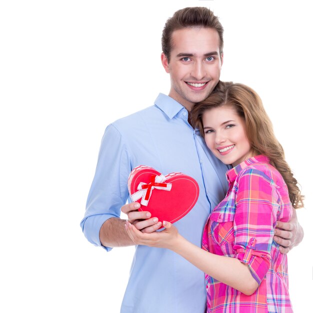 Feliz pareja joven con un regalo en un estudio aislado sobre un fondo blanco.