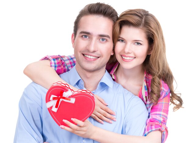 Feliz pareja joven con un regalo en un estudio aislado sobre un fondo blanco.