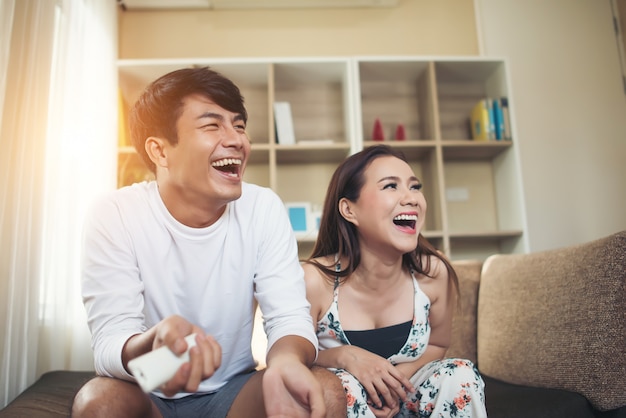 Feliz pareja joven relajante y viendo la televisión en la sala de estar