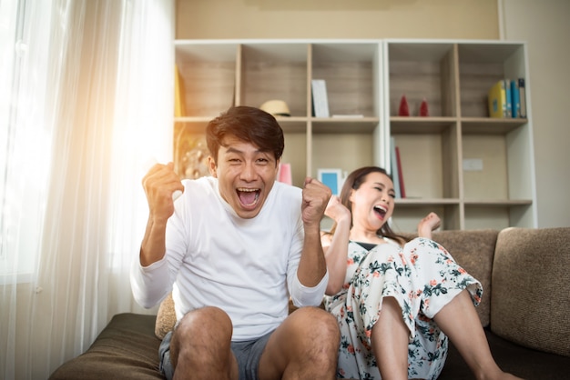 Feliz pareja joven relajante y viendo la televisión en la sala de estar