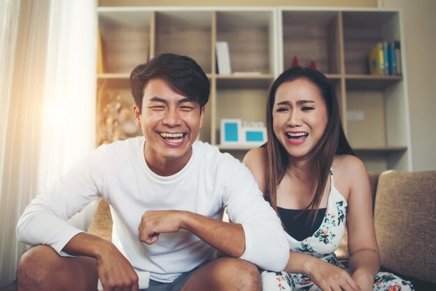 Feliz pareja joven relajante y viendo la televisión en la sala de estar