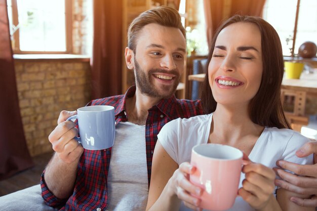 Feliz pareja joven relajarse en casa moderna sala de estar interior