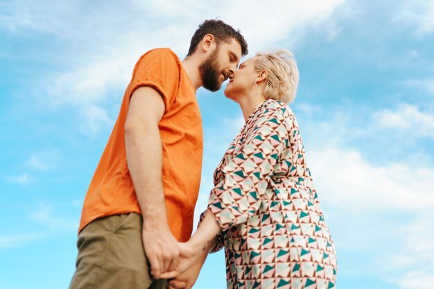 Feliz pareja joven en ropa colorida con cielo