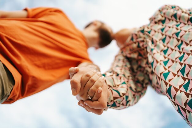 Feliz pareja joven en ropa colorida con cielo