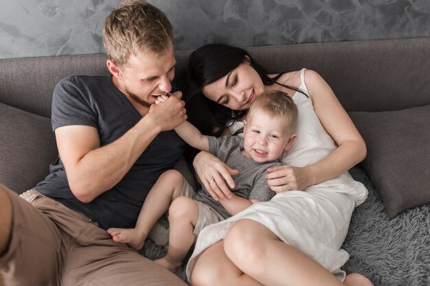 Feliz pareja joven sentada en el sofá amando a su hijo