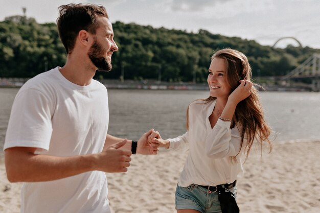 Feliz pareja de jóvenes enamorados y sonriendo mientras cubre en la playa cerca del lago