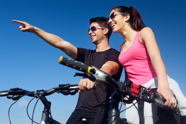Foto gratuita feliz pareja de jóvenes en un paseo en bicicleta en el campo
