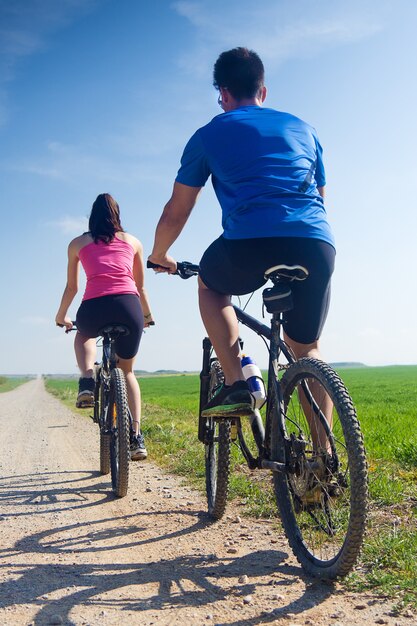 Feliz pareja de jóvenes en un paseo en bicicleta en el campo