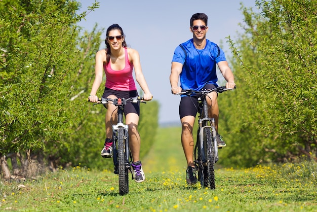 Feliz pareja de jóvenes en un paseo en bicicleta en el campo