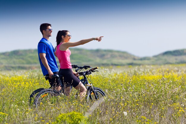 Feliz pareja de jóvenes en un paseo en bicicleta en el campo
