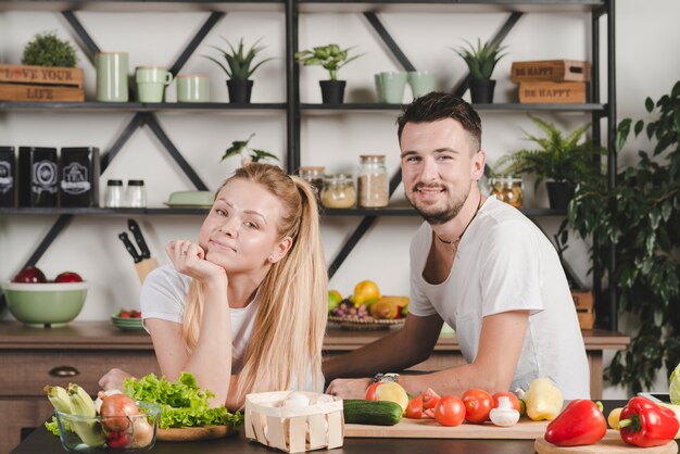 Feliz pareja de jóvenes sentados detrás del mostrador de la cocina