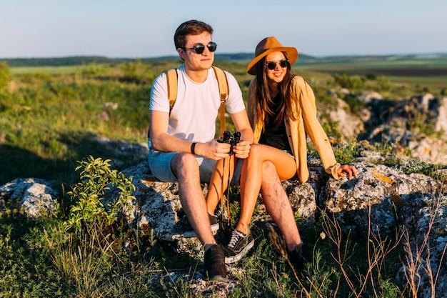 Feliz pareja de jóvenes sentados en la roca