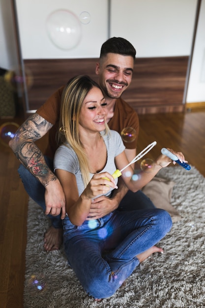 Feliz pareja jugando con burbujas en casa