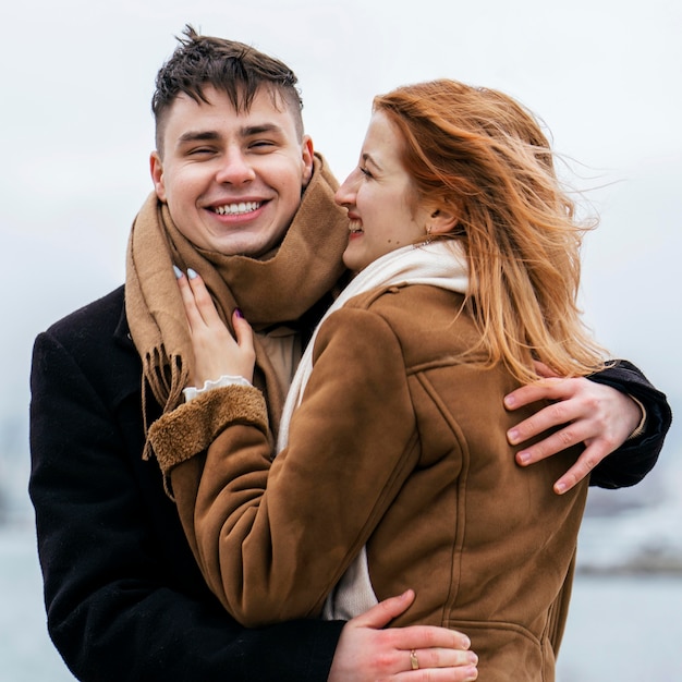 Foto gratuita feliz pareja junto al lago durante el invierno