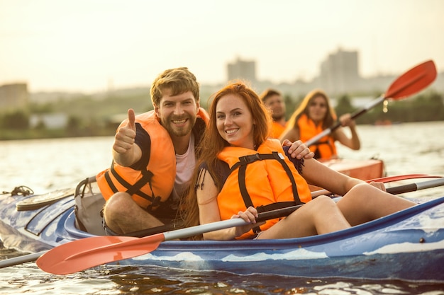 Feliz pareja en kayak en el río con puesta de sol