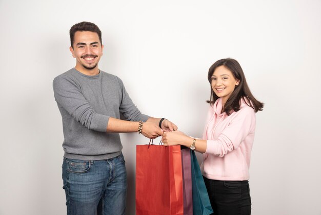 Feliz pareja llevando bolsas de la compra en blanco.