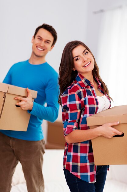 Feliz pareja llevando cajas en su nuevo hogar