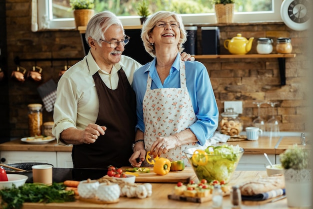 Feliz pareja madura preparando comida saludable y divirtiéndose juntos en la cocina