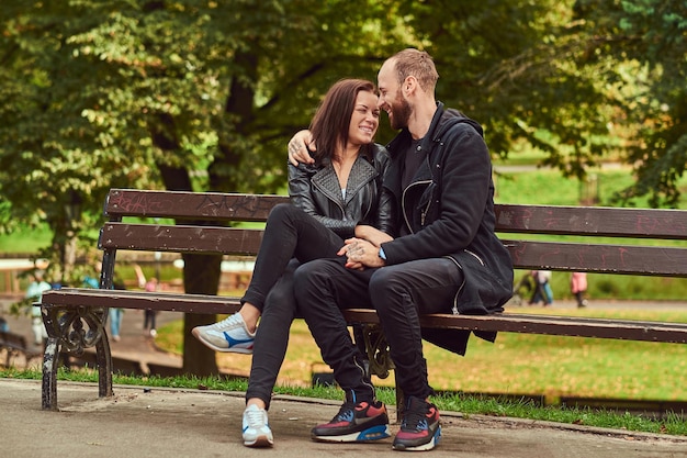 Feliz pareja moderna abrazándose en un banco en el parque. Disfrutando de su amor y la naturaleza.