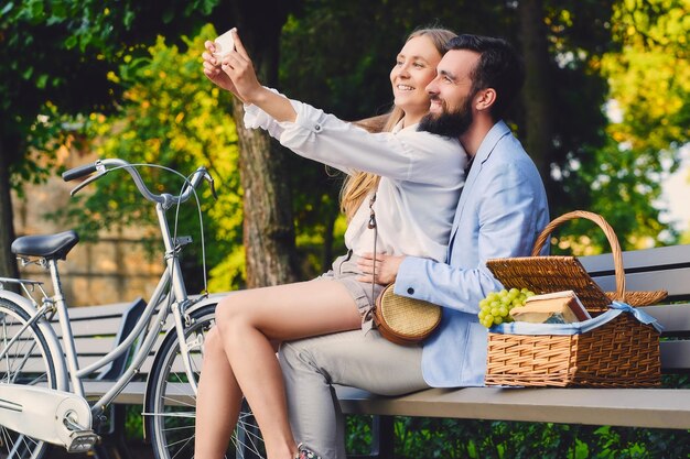 Una feliz pareja moderna en una cita se hace selfie en un parque.