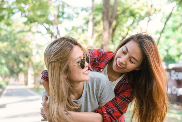 Feliz pareja de mujeres asiáticas jóvenes jugando el uno al otro mientras hacen viaje por la ciudad