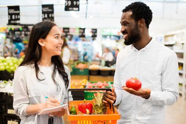 Feliz pareja multiétnica elegir productos en supermercado