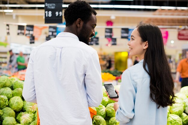 Feliz pareja multirracial elegir productos en supermercado