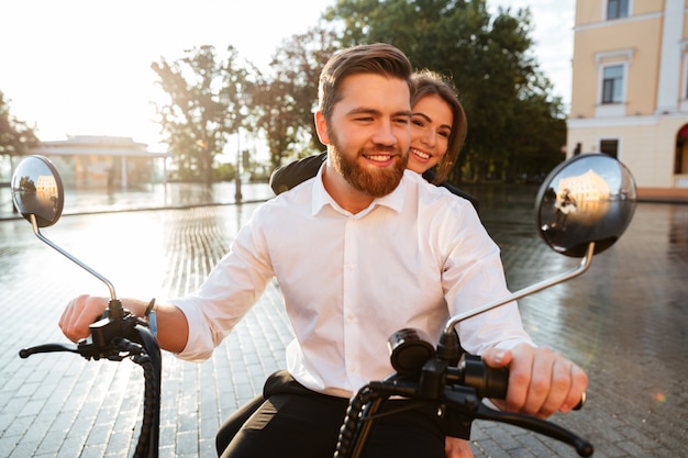 Feliz pareja de negocios monta en moto moderna en el parque