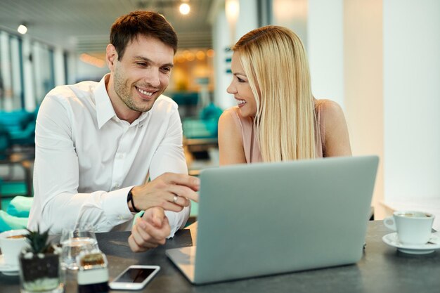 Feliz pareja de negocios trabajando en una computadora mientras está sentado en un café