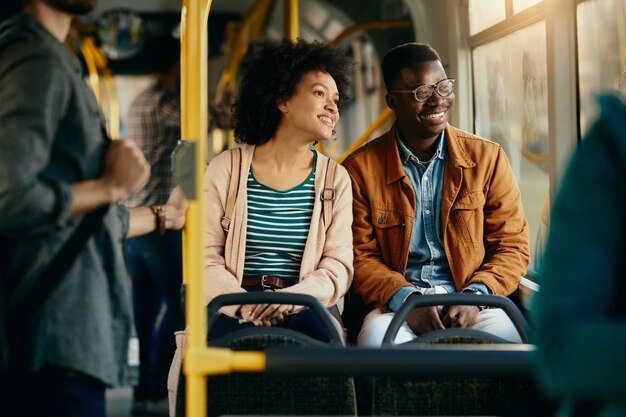 Feliz pareja negra mirando por la ventana mientras viaja en autobús