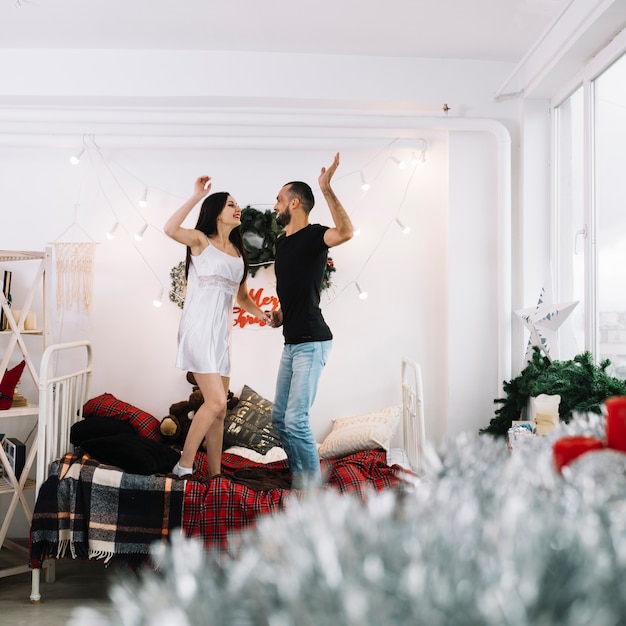 Foto gratuita feliz pareja de pie en la cama